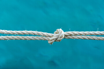 Close-up of a strong rope knot with blue water background, symbolizing connection, strength, security, and teamwork. Ideal for conceptual use in business, safety, or maritime themes.