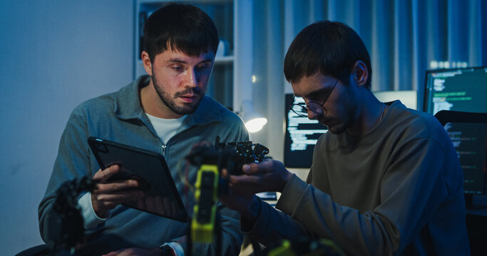 Team adult male engineer collaborate on robotic hand project using AI code solutions machine learning at tech workspace night. Artificial intelligence interface, collaboration prototype development. - Powered by Adobe