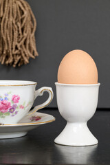 egg in its egg cup next to a pretty cup of coffee