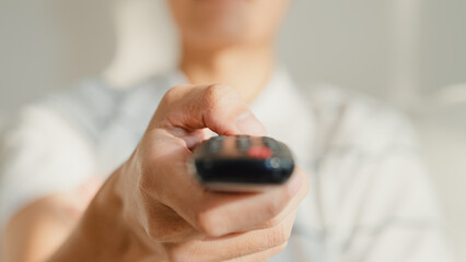 Close up young Asia male with casual cloth sit on sofa hold remote control look at television...