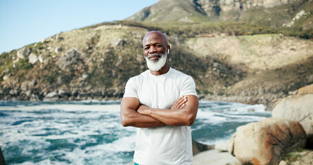 Arms crossed, fitness and portrait of black man at mountain for runner, music and health. Retirement, exercise pride and wellness with senior person outdoor for mobility training, earphones and hobby