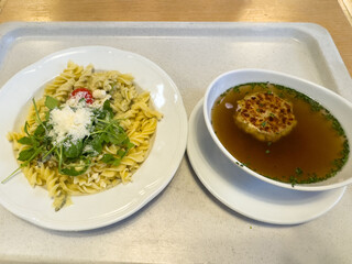 Fusilli pasta with arugula and parmesan with onion soup on tray