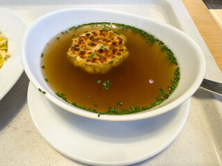 Appetizing broth with chives and dumpling in contemporary white bowl on tray