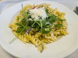 Delicious fusilli pasta with arugula and parmesan garnish