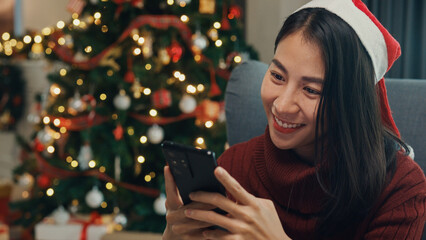 Happy Asia girl red santa hat new normal celebrate christmas party with smartphone send online...