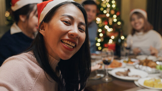 Close-up group of Asia colleague gathering New year holidays party together. Happy friend look at camera phone video call online christmas thanksgiving dinner at home, celebrate and people concept.