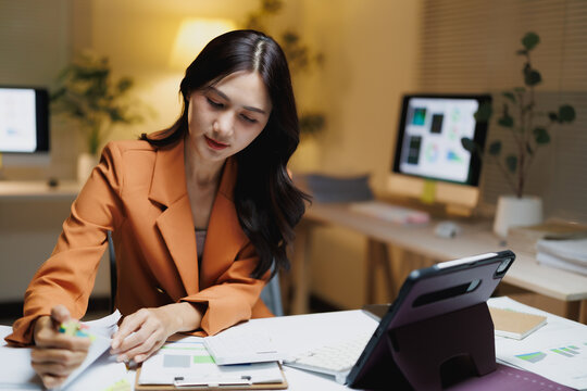 Asian businesswoman working late managing documents at office desk