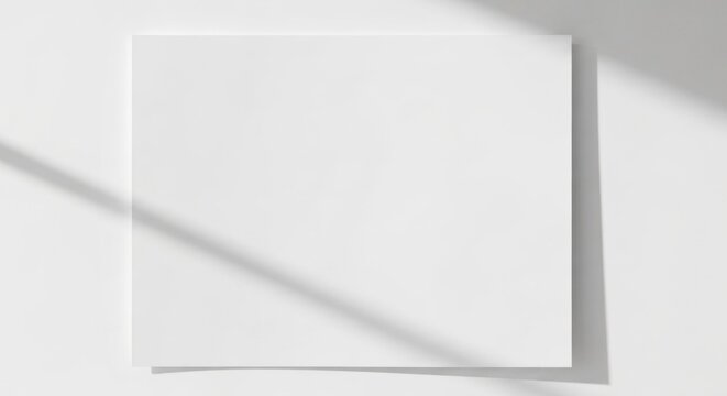 White blank square paper against a white wall with window light shadow