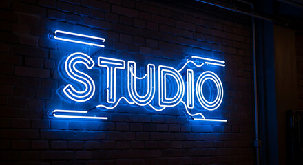 Bright blue neon studio sign glowing on a dark brick wall creating a modern artistic atmosphere in an indoor creative space