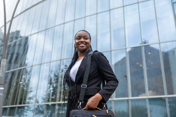Confident businesswoman walking forward with briefcase in urban setting