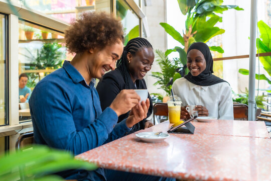 Happy diverse friends laughing together at cafe
