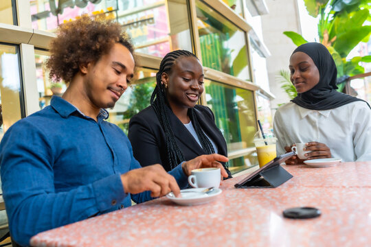 Diverse friends discussing together using a tablet in a cafe