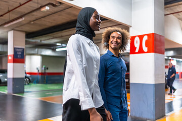 Diverse couple walking smiling in an urban parking garage