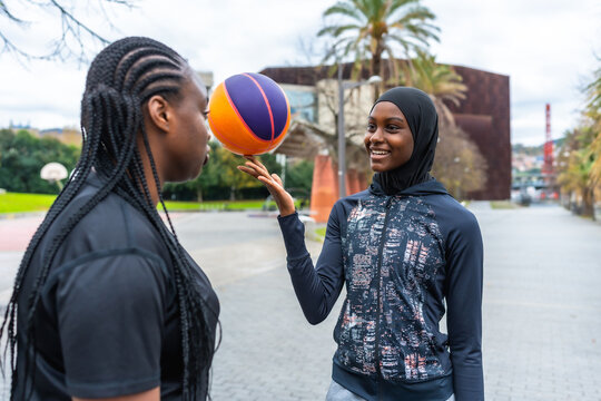 Diverse young women playing basketball with a hijab at park - Powered by Adobe