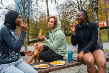 Diverse friends enjoying street food snack outdoors in park