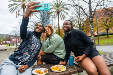 Diverse friends taking selfie and enjoying street food in park