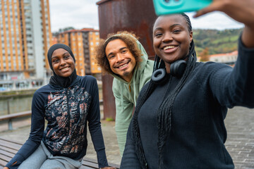 Diverse young adult friends taking selfie on bench