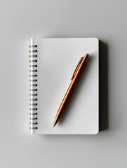 Spiral-bound notebook with a gold-colored pen resting on top of it. the notebook is white and the pen is positioned in the center of the page.