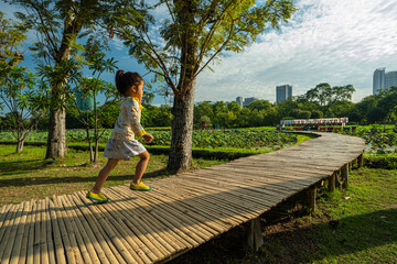 Adorable little kindergarten girl enjoy free play run on wooden pathway city park building
