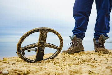 Man with metal detector on sea beach