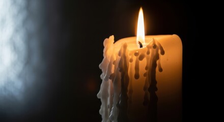 Melting white candle burning brightly in darkness