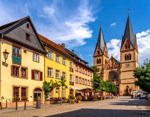 Obraz premium Sunny European streetscape with colorful buildings leading to a grand, towering church under a blue sky