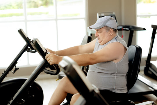 A focused man uses an elliptical machine for his workout session at a fitness center. The gym environment is well-lit, and the man’s effort shows his commitment to staying fit.