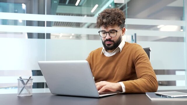 Worried businessman having difficulty making transaction using laptop while sitting at desk at workplace in modern business office. Confused worker complains about bad internet connection on computer