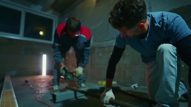 two white fabricators cutting rebar on workshop floor, dramatic sparks showering upward, protective gloves and intense focus, gritty industrial renovation scene
