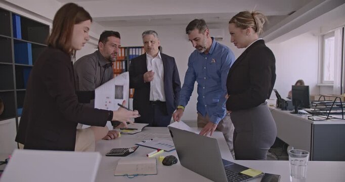 Business colleagues discuss, laugh, and collaborate on a project in the office. Teamwork and success are evident in this professional setting.