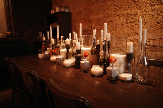 Decor on a wooden table: candles in candlesticks and loose candles, small orange roses
