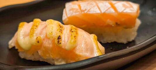 Delicious sushi platter with salmon. tuna. and roe on black plate in ambient lighting.
