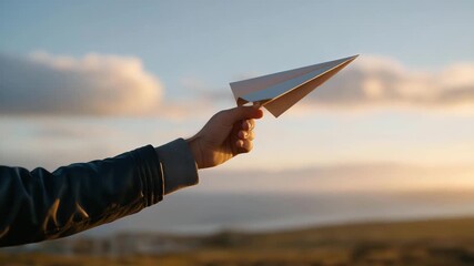Hands releasing a paper airplane into the sky during golden hour — concept of freedom, aspiration, playful creativity, and symbolic lifestyle photography. cinematic color correction, natural uneven