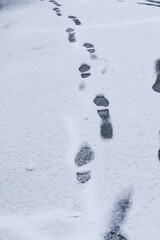 Footprints in fresh snow. Human footprints form a path across smooth fresh snow. Concept of movement metaphor, storytelling imagery, winter design, and emotional narrative.