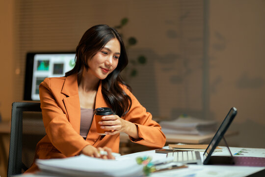Asian businesswoman working late with coffee and tablet