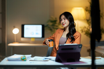 Asian businesswoman relaxing with coffee at night office