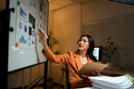 Businesswoman analyzing data charts on whiteboard in office