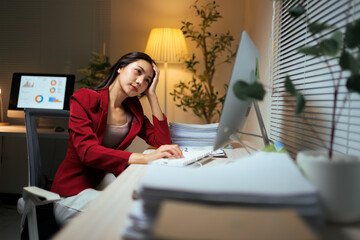 Asian woman experiencing burnout working late in office