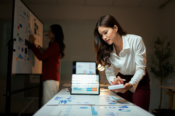 Businesswomen analyzing data charts in a late night office