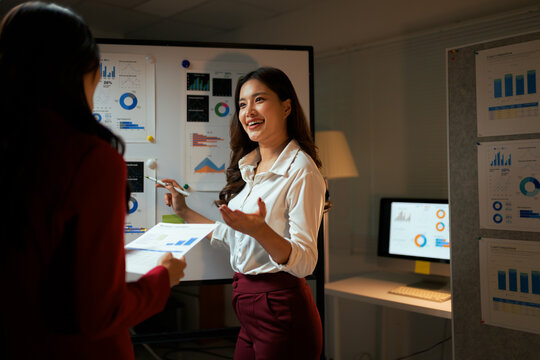 Businesswomen analyzing data during late night office presentation
