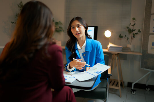 Businesswomen discussing data analysis during late night meeting - Powered by Adobe