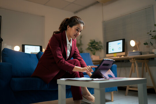 Asian businesswoman working late in modern office using digital tablet