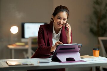 Asian businesswoman multitasking, talking on phone and using tablet
