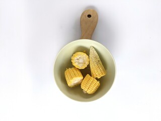 Pieces of corn sitting in a bowl on a white background