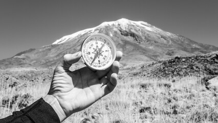 Round compass in hand on the background mountain. Concept for travelling and active lifestyle.