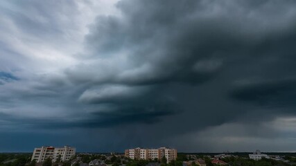 Dramatic storm clouds loom over urban cityscape with apartment buildings and trees, conveying a sense of impending weather and atmospheric change for media use.
