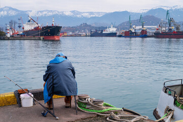 A fisherman fishes in the port of Batumi on a winter day in January.	