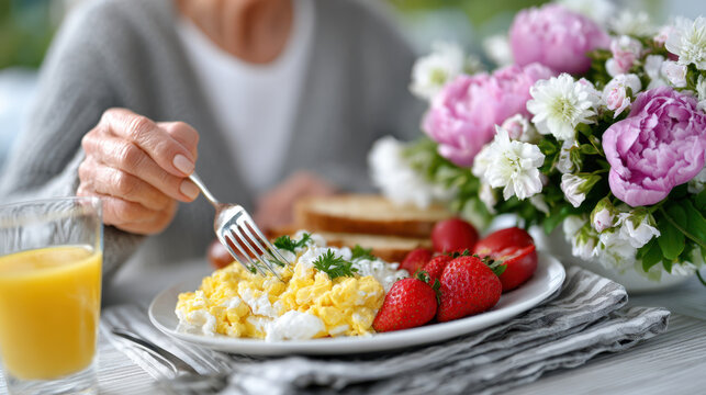 Woman's hands arranging scrumptious breakfast plate with scrambled eggs and fresh strawberries next to a vibrant flower arrangement - Powered by Adobe