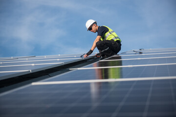 Technician installing solar panels on factory roof for green energy. A skilled technician in safety...