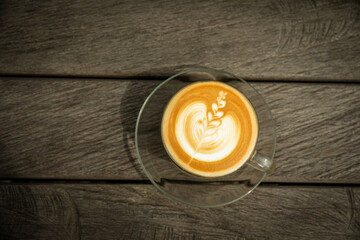 Latte art displayed in a glass cup on a wooden surface
